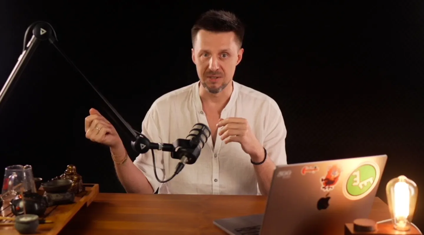 Alex Samson speaking in a remote session, at a desk with a microphone and laptop